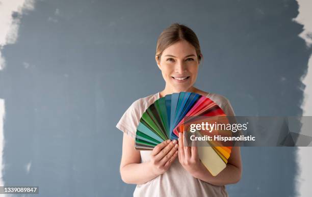 glückliche frau, die ihr haus malt und eine farbe aus einer palette wählt - farbprobe stock-fotos und bilder