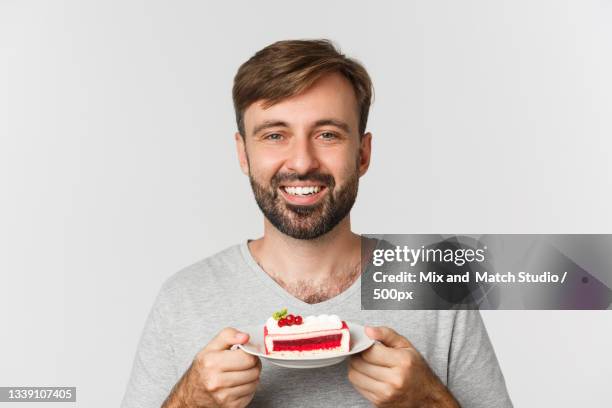 portrait of smiling young man holding cake against white background - cake face bildbanksfoton och bilder