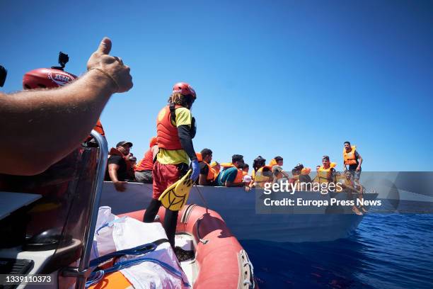 Members of the NGO Open Arms traveling on the boat 'Astral' assist migrants traveling on a skiff, on September 8 in the Mediterranean Sea, in the...
