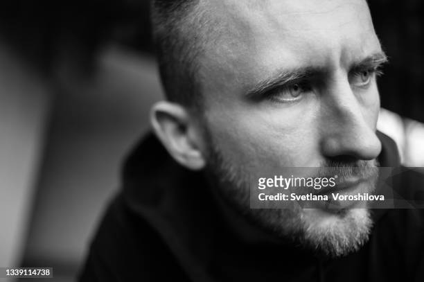 сlose-up black and white portrait of a young bearded man looking past the camera with emotional pain in his eyes. - actor photos ストックフォトと画像