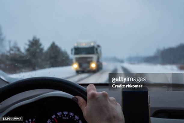 woman driving a car on a snowy slippery road at dusk - schneeregen stock-fotos und bilder