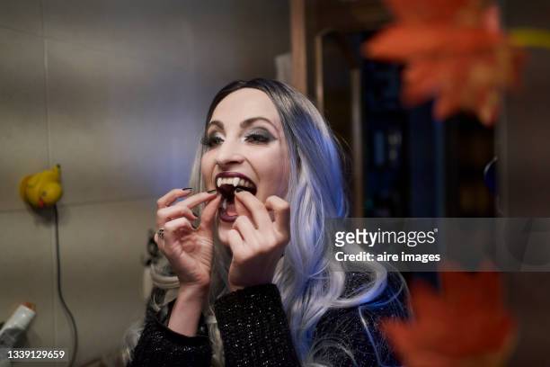 close-up of woman with halloween costume puts on false vampire teeth - historische kleding stockfoto's en -beelden