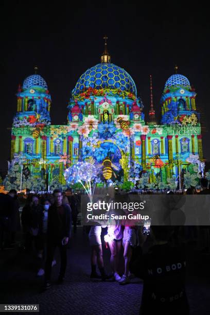 Visitors gather to look at the Dom Cathedral that is bathed in an artistic light mural during the Festival of Lights on September 08, 2021 in Berlin,...