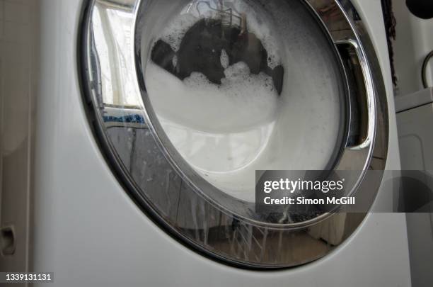 front loading washing machine with too many suds inside it - washing machine with bubbles stock pictures, royalty-free photos & images