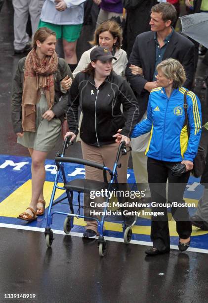 Boston Marathon bombing victim Erika Brannock, who lost her left leg in the blast, walks across the finish line with her mother, Carol Downing after...