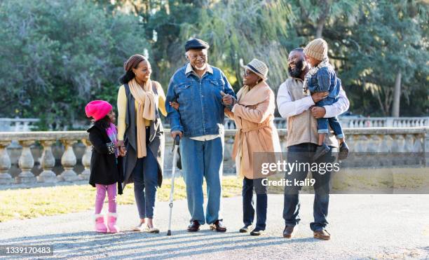 three generation african-american family walking in park - walking cane stockfoto's en -beelden