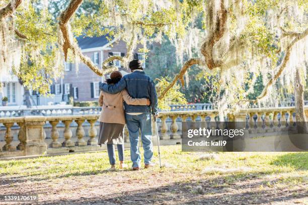 senior african-american couple walk in park on sunny day - walking stick stock pictures, royalty-free photos & images