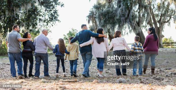 rear view of multi-generation hispanic family walking - arm around friend back stock pictures, royalty-free photos & images