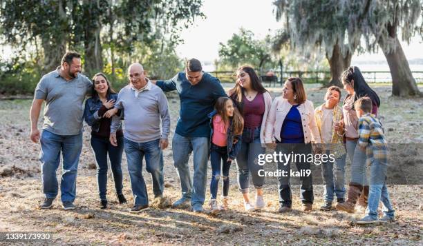 multi-generation hispanic family walking at park side by side - family reunion stock pictures, royalty-free photos & images