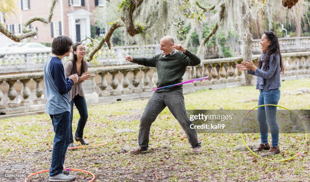 Familia multirracial jugando con aros de plástico en el parque