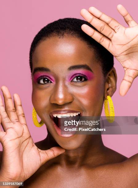 excited young african woman with mouth open frames face with hands - eye shadow imagens e fotografias de stock