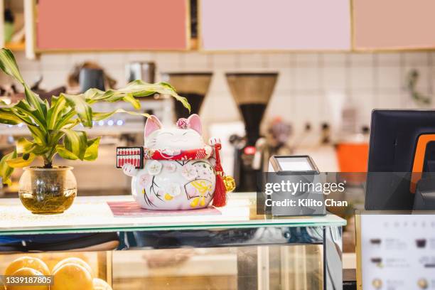 maneki neko placed at the cafe checkout counter to bring fortune and wealth - maneki neko 個照片及圖片檔