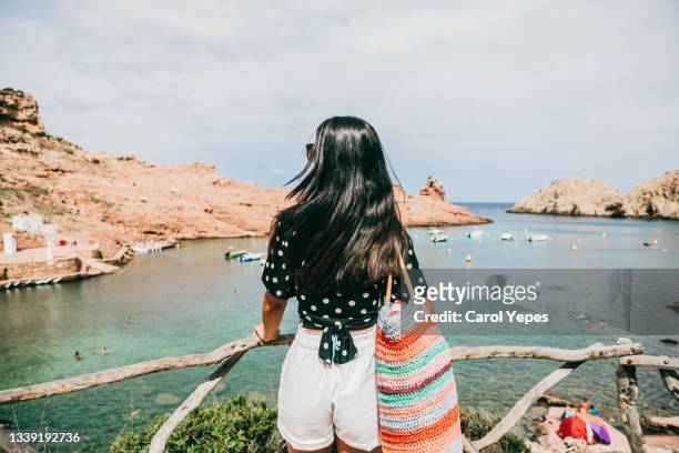 beautiful latina standing in a balcony in cala morell,minorca,balearic islands; spain - beach holiday stock-fotos und bilder