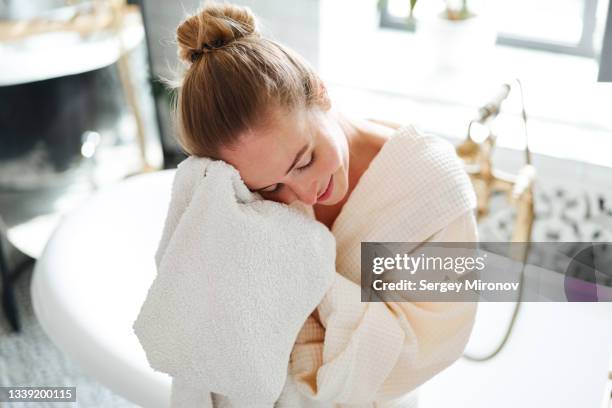 woman wipes face with a towel after taking a bath - serviette de bain photos et images de collection
