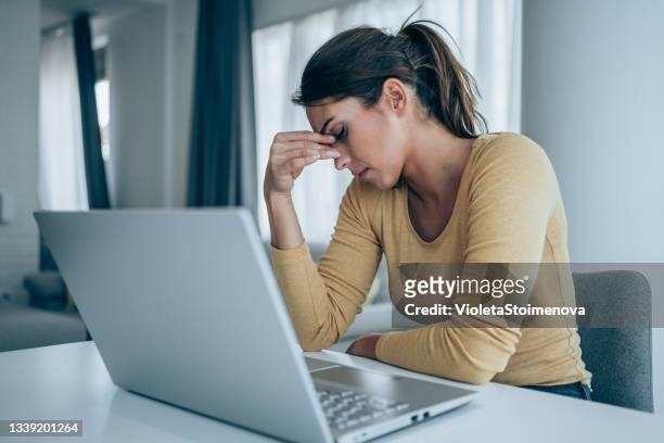 gestresste geschäftsfrau mit laptop zu hause. - arbeitslosigkeit stock-fotos und bilder