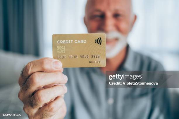 um homem segurando um cartão de crédito. - shopaholic - fotografias e filmes do acervo