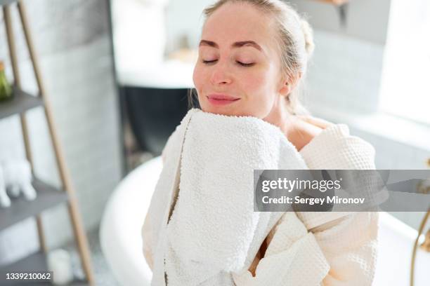 woman wiping face in bathroom - gesichtsreinigung stock-fotos und bilder