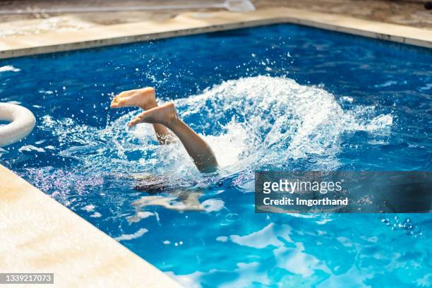 teenage girl jumping into swimming pool on summer day. - swimming pool jump stock pictures, royalty-free photos & images