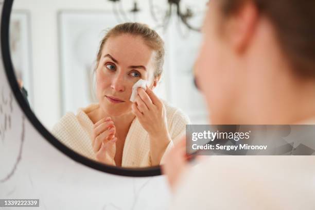woman cleaning face with wet wipes in bathroom - facial cleanser stockfoto's en -beelden