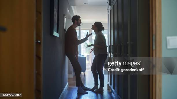 Young Couple Arguing and Fighting. Domestic Violence Scene of Emotional abuse, Stressed Woman and aggressive Man Having Almost Violent Argument in a Dark Claustrophobic Hallway of Apartment.