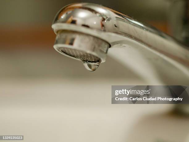 close-up shot of water drop hanging from faucet - 浄水 ストックフォトと画像