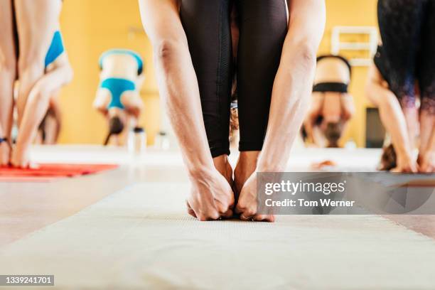 woman leaning forward gripping feet during yoga - touching toes stock pictures, royalty-free photos & images