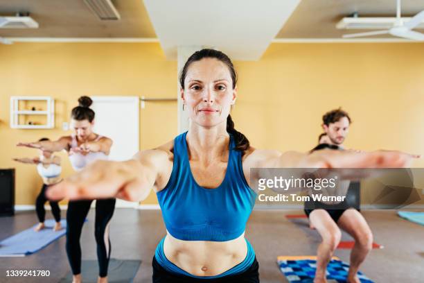 yoga instructor posing in front of class - bikram yoga stock pictures, royalty-free photos & images