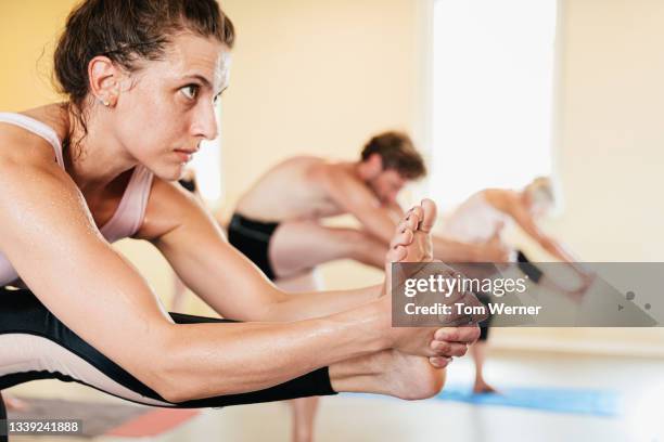 flexible woman posing during hot yoga class - bikram yoga stock-fotos und bilder