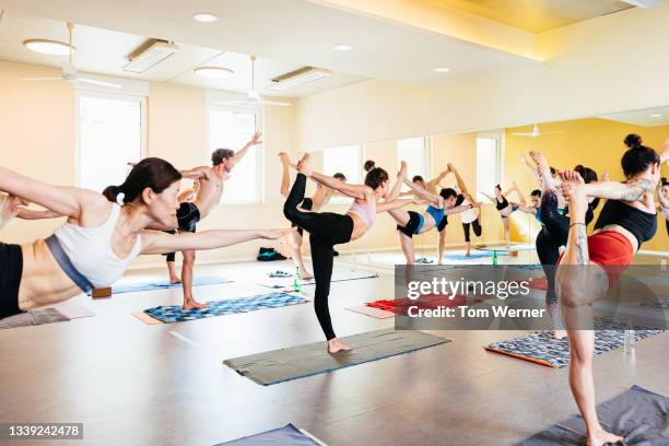 busy yoga class with patrons posing - hot yoga stock pictures, royalty-free photos & images