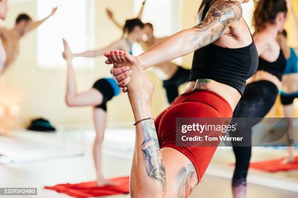 close up of woman holding foot during hot yoga class - running shorts stockfoto's en -beelden