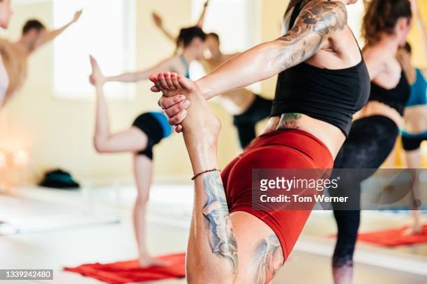 close up of woman holding foot during hot yoga class - running shorts stock pictures, royalty-free photos & images