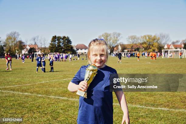 child holding a trophy after a football match - sports trophy stock pictures, royalty-free photos & images