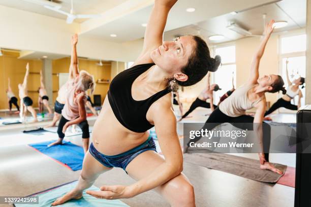 pregnant woman leaning to one side during yoga class - crecimiento estirón fotografías e imágenes de stock