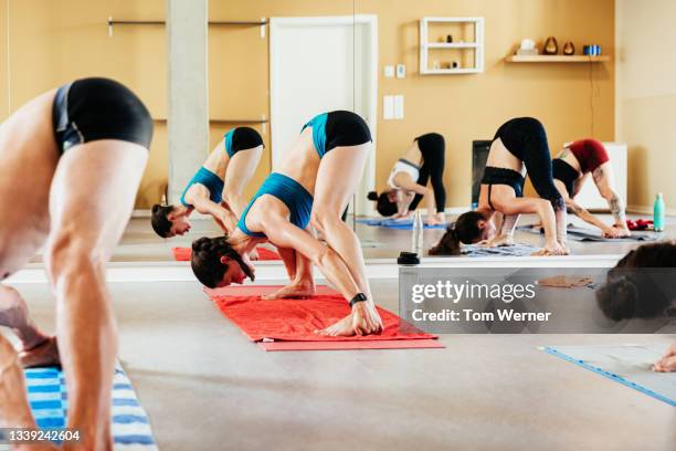 yoga class with people bending over gripping feet - woman running shorts stock pictures, royalty-free photos & images