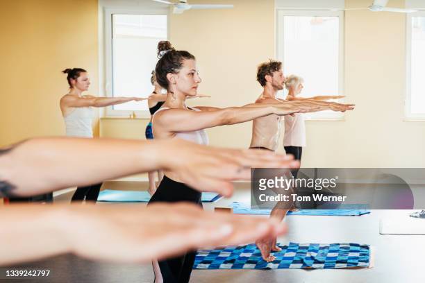 people standing with arms pointing forward during yoga class - tiptoe imagens e fotografias de stock