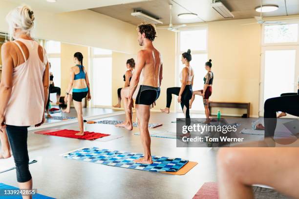 people standing on one leg during yoga class - bikram yoga stock pictures, royalty-free photos & images