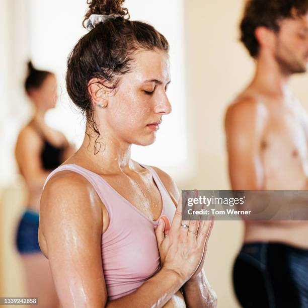 woman with hands together in prayer during hot yoga - 汗 ストックフォトと画像
