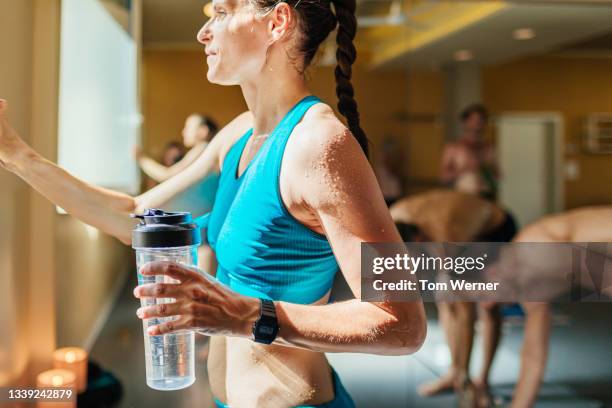 woman taking break from hot yoga for water - hot yoga stock pictures, royalty-free photos & images