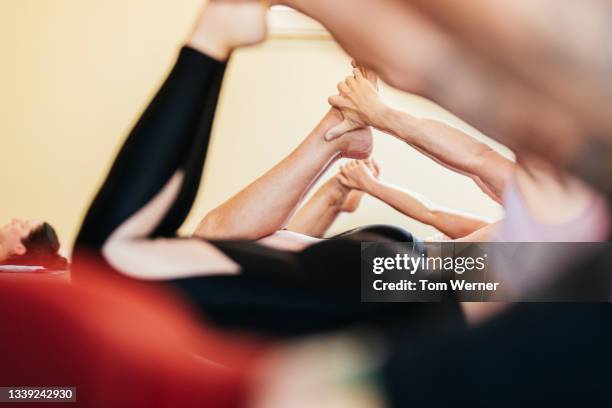 view of people posing through someone's arms in yoga class - camera point of view stock-fotos und bilder