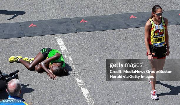 Second place Desiree Davila of USA walks off as winner Caroline Kilel lays down after crossing the finish line during the 115th Boston Marathon...