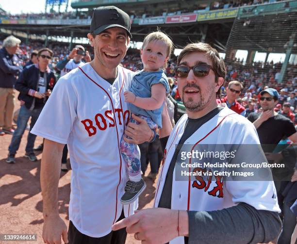 Boston Marathon survivor Jeff Bauman, right and actor Jake Gyllenhaal holding Bauman's daughter Nora before throwing out the first pitch before the...