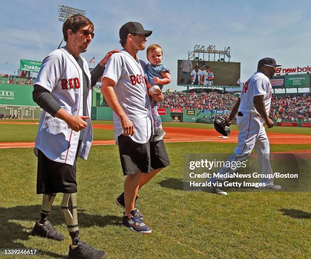 Boston Marathon survivor Jeff Bauman and actor Jake Gyllenhaal holding Bauman's daughter Nora along with Boston Red Sox designated hitter David...