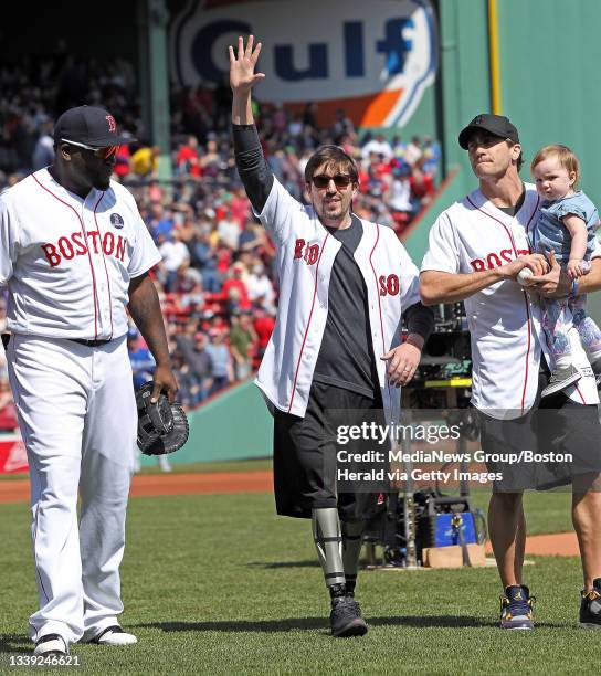 Boston Red Sox designated hitter David Ortiz, Boston Marathon survivor Jeff Bauman and actor Jake Gyllenhaal holding Bauman's daughter Nora walk off...