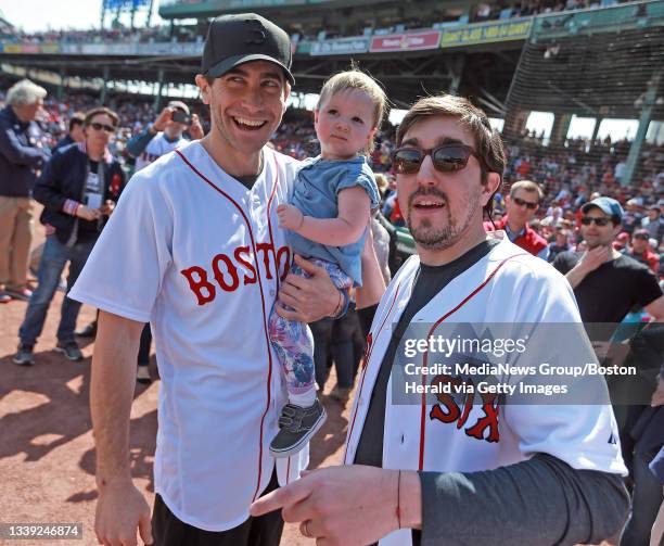 Boston Marathon survivor Jeff Bauman, right and actor Jake Gyllenhaal holding Bauman's daughter Nora before throwing out the first pitch before the...