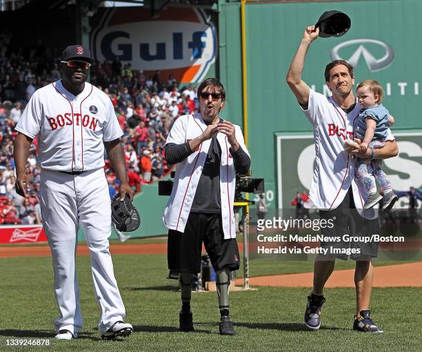 Boston Red Sox designated hitter David Ortiz, Boston Marathon survivor Jeff Bauman and actor Jake Gyllenhaal holding Bauman's daughter Nora walk off...