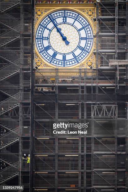 Two people walk down the steps past the restored clock face on Elizabeth Tower, displaying the original Prussian blue colour of the hands, on...