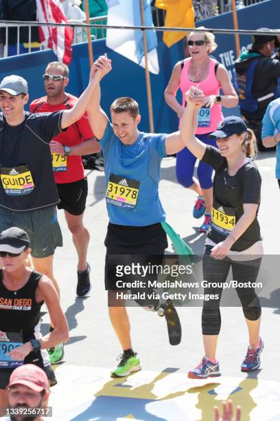 Boston Marathon bombing survivor, Patrick Downes, center, of Cambridge, crosses the finish line of the 2016 Boston Marathon on Boylston Street on...
