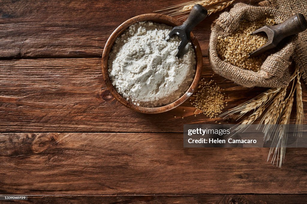 Wooden bowl and burlap sack filled with wheat flour