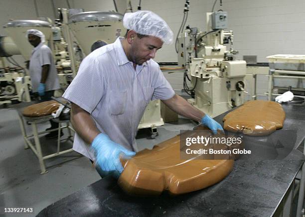 Rodolfo Rivera bends a block of caramel just prior to feeding it into a machine that that cuts it into cubes at the New England Confectionery Company...