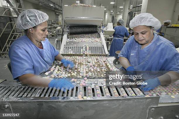 Teresa Barbosa, left, and Carolyn DeGraffenreid, right, process NECCO wafers at the New England Confectionery Company factory floor.